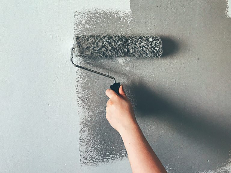 Mulher a pintar parede com rolo de pintura